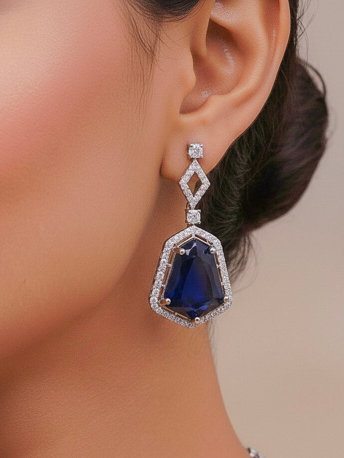 Close-up of a woman wearing an ornate Western Blue (Silver Polish) Diamond jewellery set and earrings with American Diamond and Colored Stones. Festive Diwali outfit styled with an American diamond artificial necklace. Close-up of a party look featuring a premium American diamond necklace.