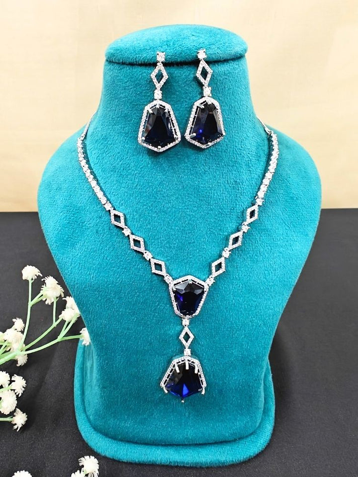 Close-up of a woman wearing an ornate Western Blue (Silver Polish) Diamond jewellery set and earrings with American Diamond and Colored Stones. Festive Diwali outfit styled with an American diamond artificial necklace. Close-up of a party look featuring a premium American diamond necklace.