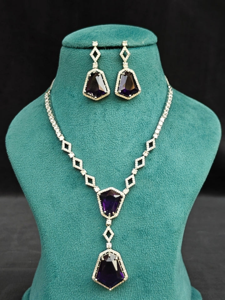Close-up of an ornate Western Purple (Silver Polish) Diamond jewellery set and earrings with American Diamond and Colored Stones. Festive Diwali outfit styled with an American diamond artificial necklace. Close-up of a party look featuring a premium American diamond necklace.