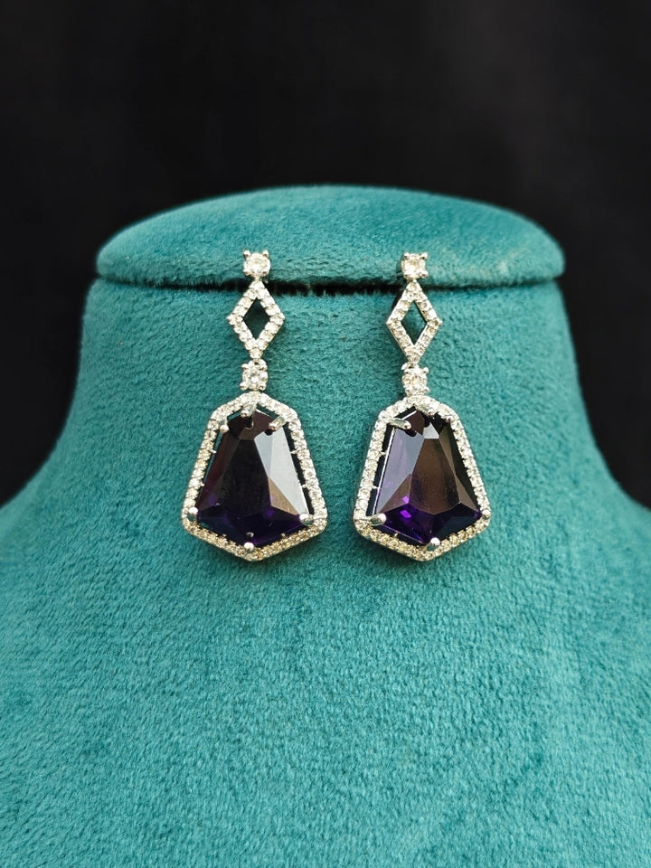 Close-up of an ornate Western Purple (Silver Polish) Diamond jewellery set and earrings with American Diamond and Colored Stones. Festive Diwali outfit styled with an American diamond artificial necklace. Close-up of a party look featuring a premium American diamond necklace.