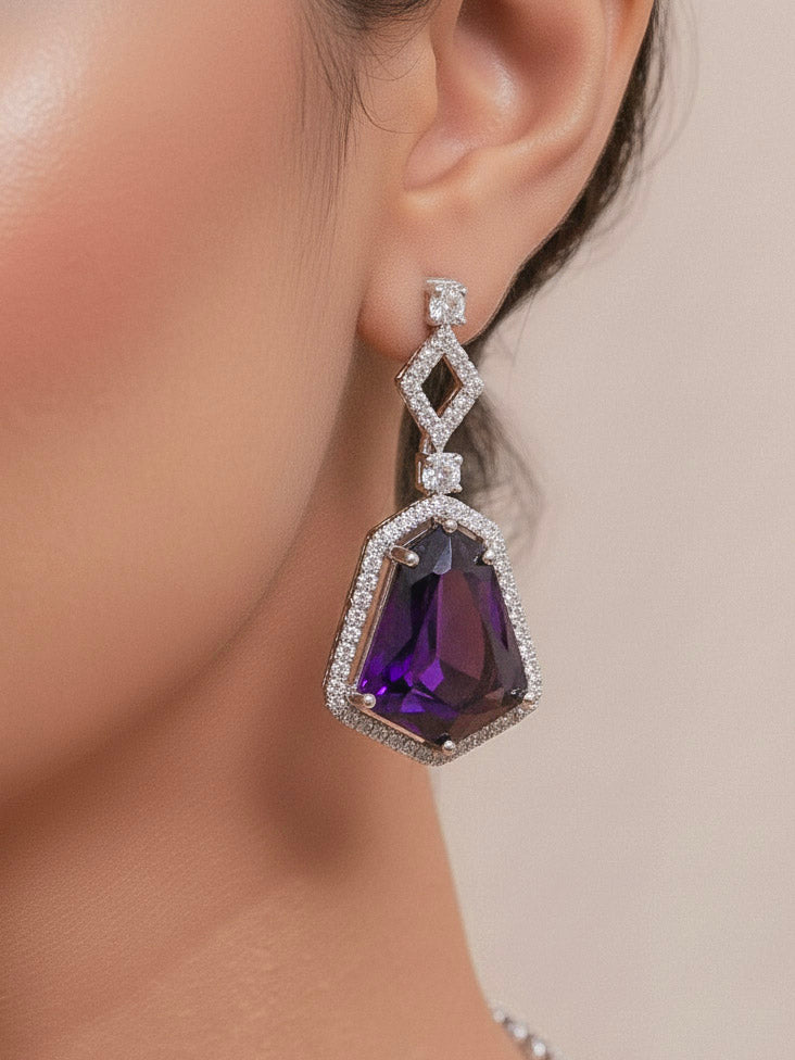 Close-up of a woman wearing an ornate Western Purple (Silver Polish) Diamond jewellery set and earrings with American Diamond and Colored Stones. Festive Diwali outfit styled with an American diamond artificial necklace. Close-up of a party look featuring a premium American diamond necklace.