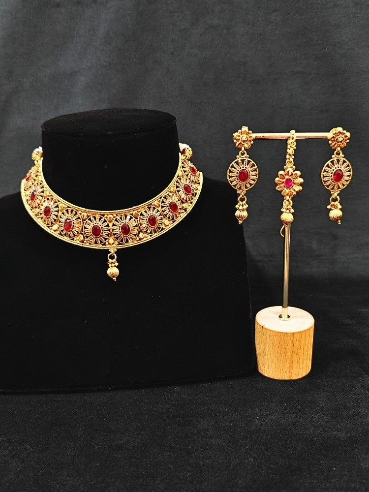 Close-up of an ornate traditional Red Diamond gold Polish Choker jewellery set and earrings and maangtikka with Baguette American Diamonds and Red Colored Stones. A luxury American diamond necklace set styled beautifully for a wedding guest look in India. Close-up of a featuring an anti-tarnish American diamond artificial necklace.