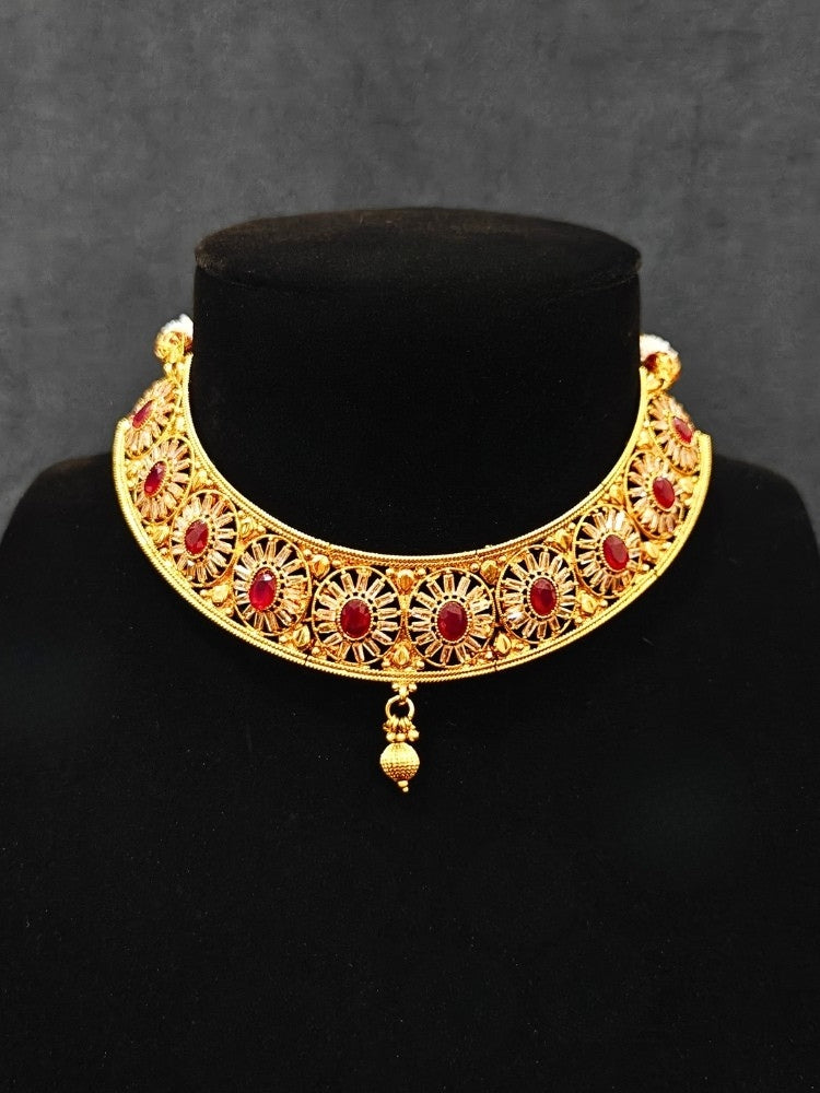 Close-up of an ornate traditional Red Diamond gold Polish Choker jewellery set and earrings and maangtikka with Baguette American Diamonds and Red Colored Stones. A luxury American diamond necklace set styled beautifully for a wedding guest look in India. Close-up of a featuring an anti-tarnish American diamond artificial necklace.