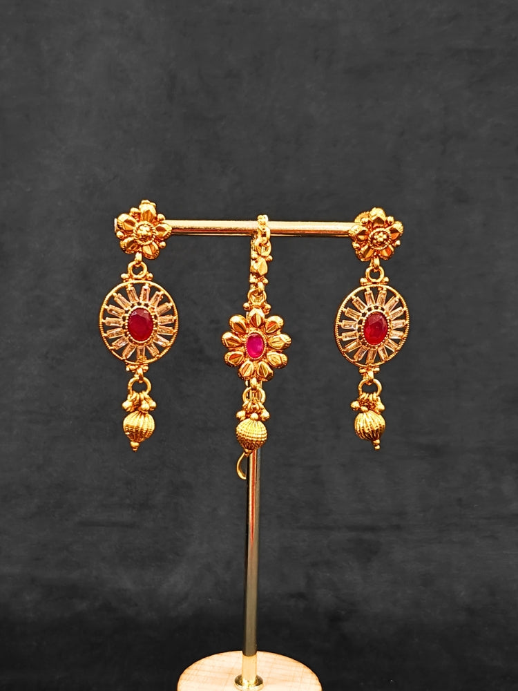 Close-up of an ornate traditional Red Diamond gold Polish Choker jewellery set and earrings and maangtikka with Baguette American Diamonds and Red Colored Stones. A luxury American diamond necklace set styled beautifully for a wedding guest look in India. Close-up of a featuring an anti-tarnish American diamond artificial necklace.