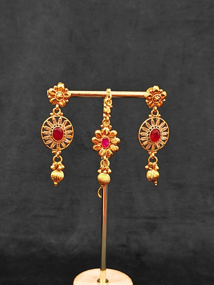 Close-up of an ornate traditional Red Diamond gold Polish Choker jewellery set and earrings and maangtikka with Baguette American Diamonds and Red Colored Stones. A luxury American diamond necklace set styled beautifully for a wedding guest look in India. Close-up of a featuring an anti-tarnish American diamond artificial necklace.