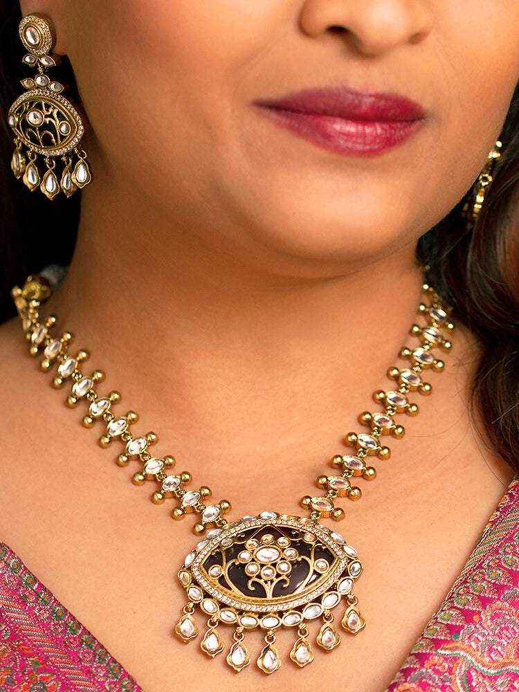 Close-up of a woman wearing an ornate traditional (Mehendi Polish Antique Finish) Dark Purple Collar jewellery set and earrings with Kundan, Monalisa Stone, Colored Stones and American Diamond. Woman wearing trending Kundan artificial jewelry for wedding season in India. Festive Diwali outfit paired with a premium Kundan jewelry piece.