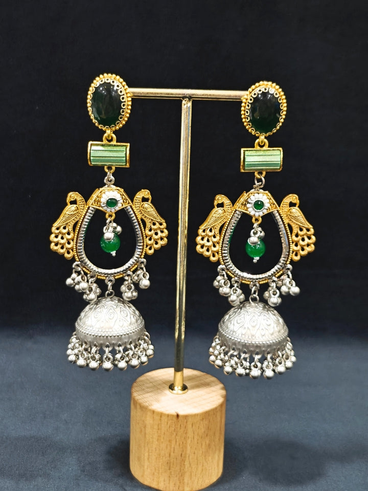 Close-up of an ornate traditional (Gold and Silver Polish) Green Long Earrings set with Green Colored Stone. Close-up of anti-tarnish artificial Oxidised earrings for festive celebrations. Festive saree look completed with premium imitation Oxidised earrings.