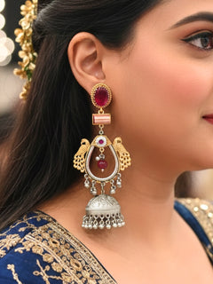 Close-up of a woman wearing an ornate traditional (Gold and Silver Polish) Red Long Earrings set with Green Colored Stone. Close-up of anti-tarnish artificial Oxidised earrings for festive celebrations. Festive saree look completed with premium imitation Oxidised earrings.