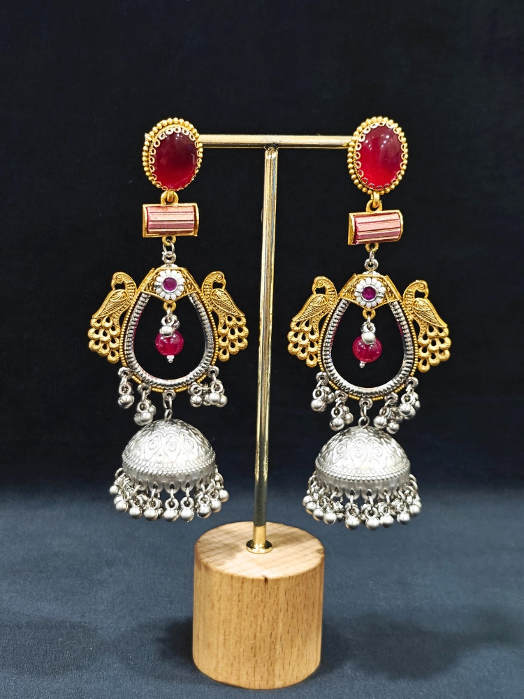 Close-up of an ornate traditional (Gold and Silver Polish) Red Long Earrings set with Green Colored Stone. Close-up of anti-tarnish artificial Oxidised earrings for festive celebrations. Festive saree look completed with premium imitation Oxidised earrings.
