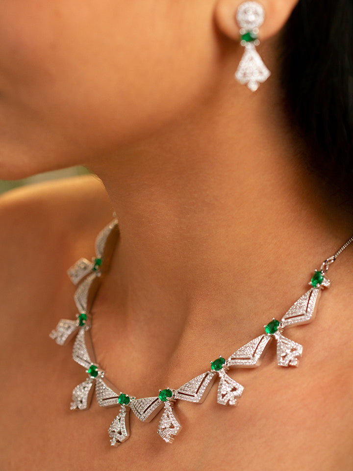 Elegant woman wearing a luxurious artificial diamond necklace with green colored stone and  matching earrings, perfect for high-profile wedding receptions and formal galas. This high-end artificial diamond jewelry set combines style, elegance, and affordability for special occasions.