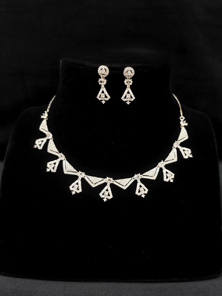 Close-up of an ornate Western White (Silver Polish) Collar Diamond jewellery set and earrings with American Diamond. Reception-ready look featuring a statement American diamond jewelry set. Party wear outfit completed with a lightweight American diamond necklace.