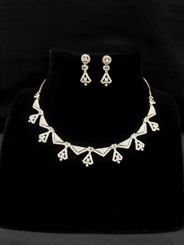 Close-up of an ornate Western White (Silver Polish) Collar Diamond jewellery set and earrings with American Diamond. Reception-ready look featuring a statement American diamond jewelry set. Party wear outfit completed with a lightweight American diamond necklace.