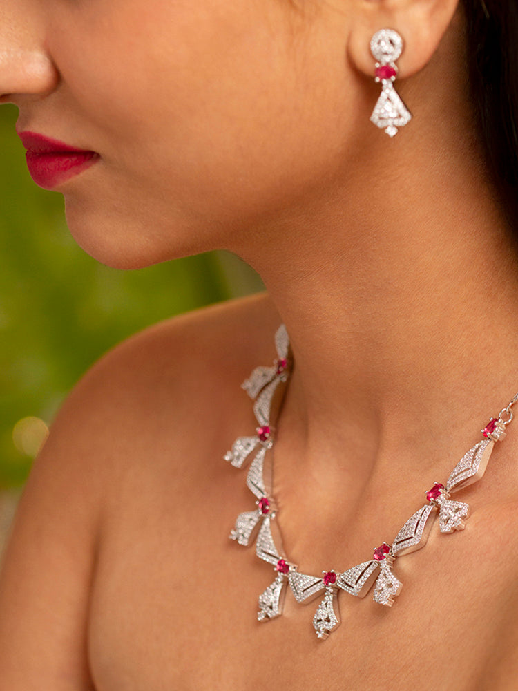 A beautiful woman wearing an elegant artificial diamond necklace with red colored stone and matching earrings. This premium artificial diamond jewelry set is perfect for special occasions, from Indian weddings to engagement parties, offering sophisticated glamour without the high price tag.