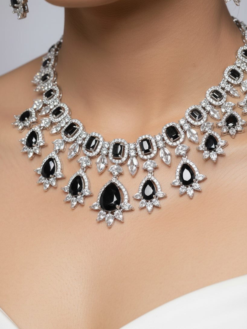 "A woman in a traditional saree, wearing a gorgeous artificial diamond and black colored stone necklace paired with diamond earrings. This artificial diamond jewelry set offers a traditional yet modern touch for Indian brides, designed to add elegance and sophistication to any occasion."