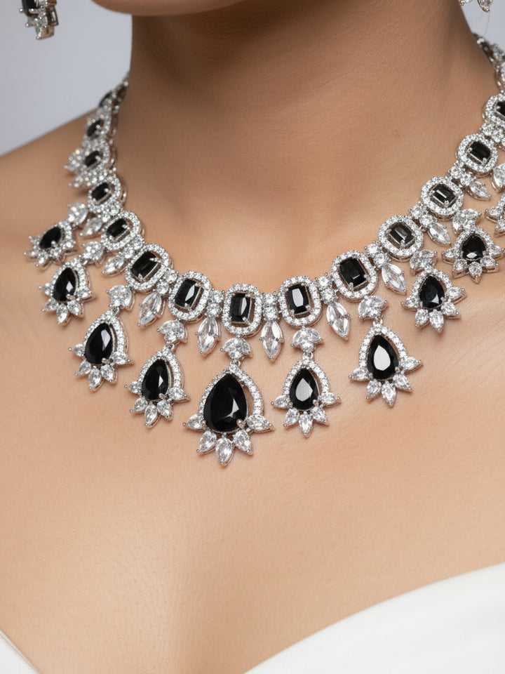 "A woman in a traditional saree, wearing a gorgeous artificial diamond and black colored stone necklace paired with diamond earrings. This artificial diamond jewelry set offers a traditional yet modern touch for Indian brides, designed to add elegance and sophistication to any occasion."