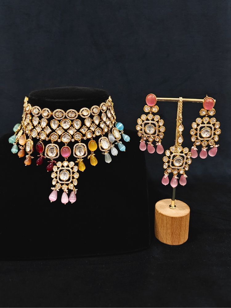 Close-up of an ornate traditional (Gold Polish) Choker jewellery set and earrings with Polki, American Diamond, Colored Stones and Tumble Beads. Wedding guest wearing a statement Polki artificial necklace for a reception party. Woman wearing trending Polki artificial jewelry for the wedding season in India.