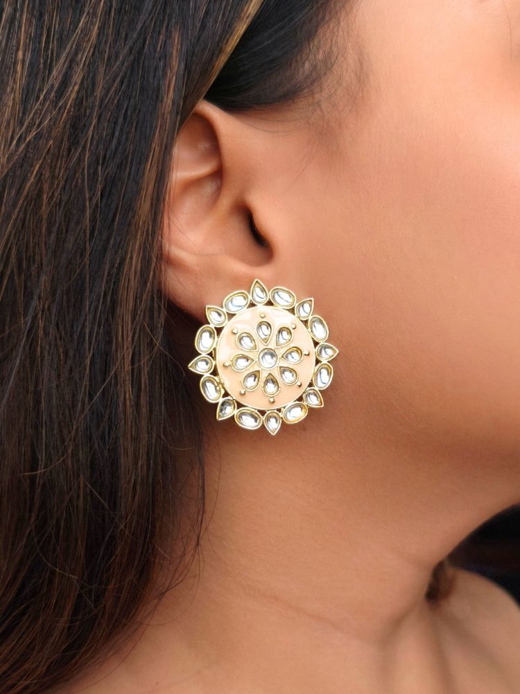 The Audrey Peach stud Earrings are round, gold-toned Kundan earrings, shown on a side face of a woman. 