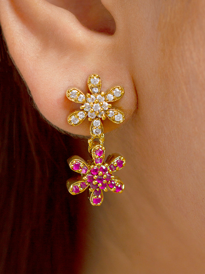 A woman with straight brown hair wears the Aurelia Choker Necklace Set—gold party jewelry with colorful floral designs and American diamonds. She pairs it with matching earrings, bright pink lipstick, and a slight smile.