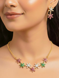 Woman wearing the Aurelia gold choker necklace set with green, pink and white stones, and matching earrings.
