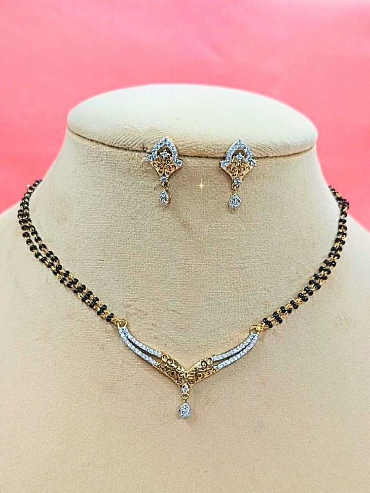 Avantika Mangalsutra—a gold necklace with black mangalsutra beads and matching earrings, pendant featuring sparkling American Diamonds—set against a cream dummy, perfect for your wedding ceremony dress. Diamond mangalsutra. Modern mangalsutra. 