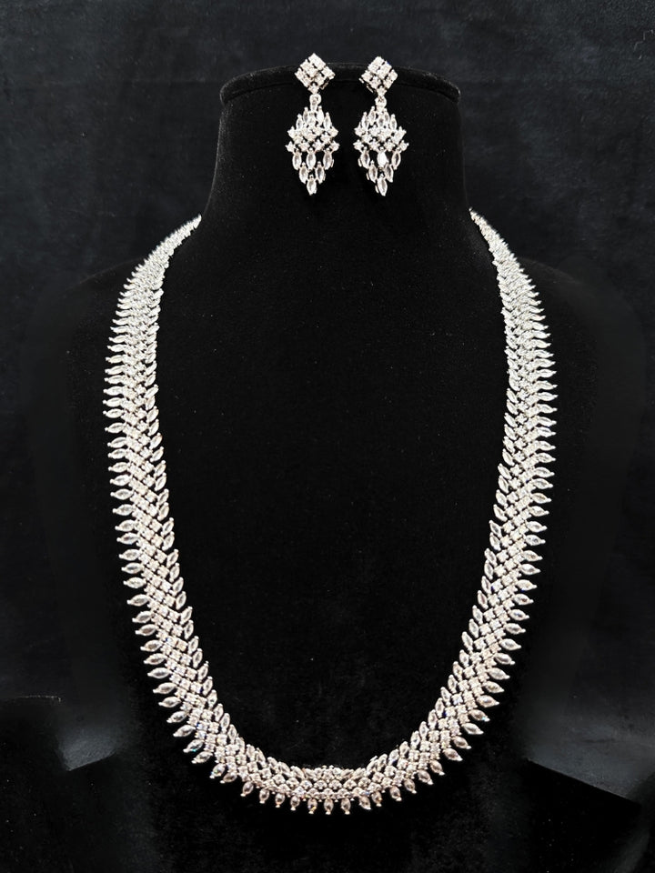 Close-up of an ornate Western Dimaond Silver jewellery set and earrings with American Diamond. Party wear outfit completed with a lightweight American diamond necklace. Styling American diamond necklace with an off-shoulder gown for a reception.