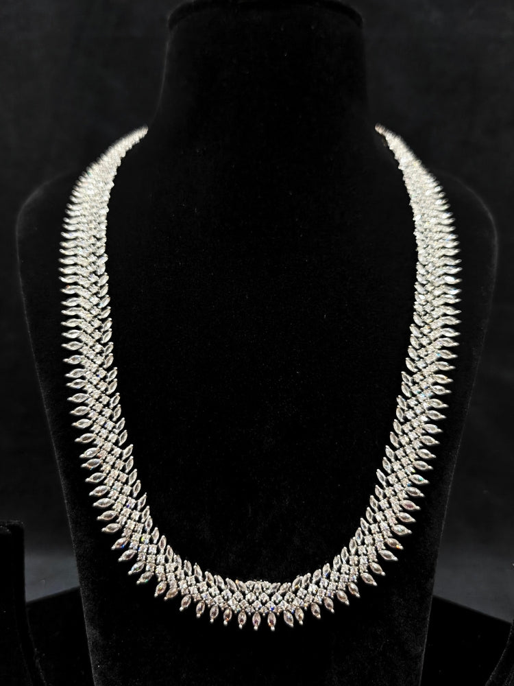 Close-up of an ornate Western Dimaond Silver jewellery set and earrings with American Diamond. Party wear outfit completed with a lightweight American diamond necklace. Styling American diamond necklace with an off-shoulder gown for a reception.