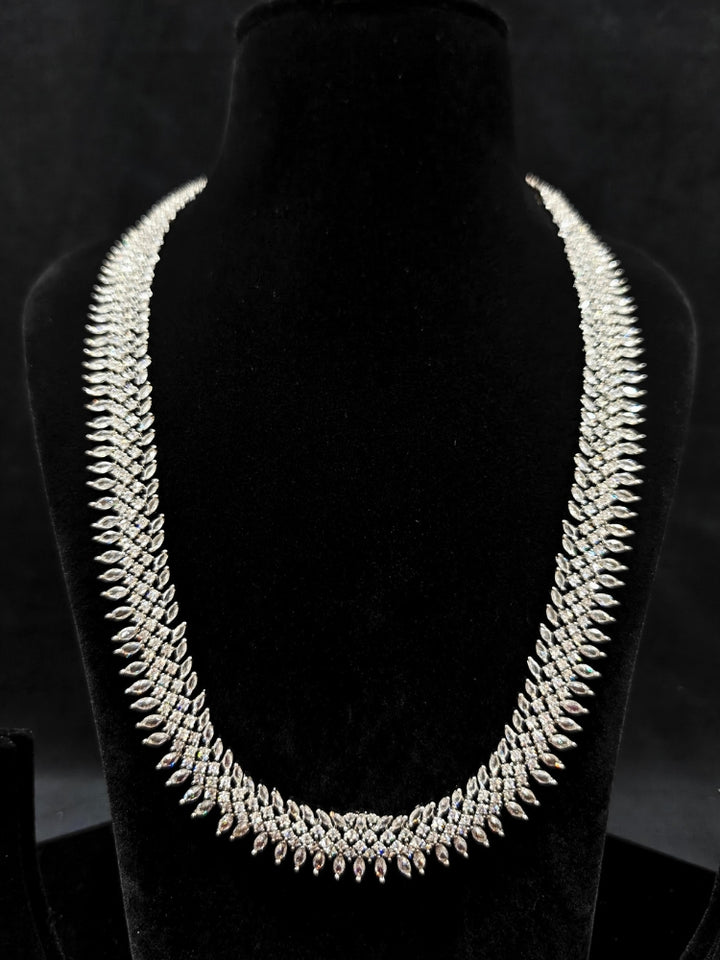 Close-up of an ornate Western Dimaond Silver jewellery set and earrings with American Diamond. Party wear outfit completed with a lightweight American diamond necklace. Styling American diamond necklace with an off-shoulder gown for a reception.