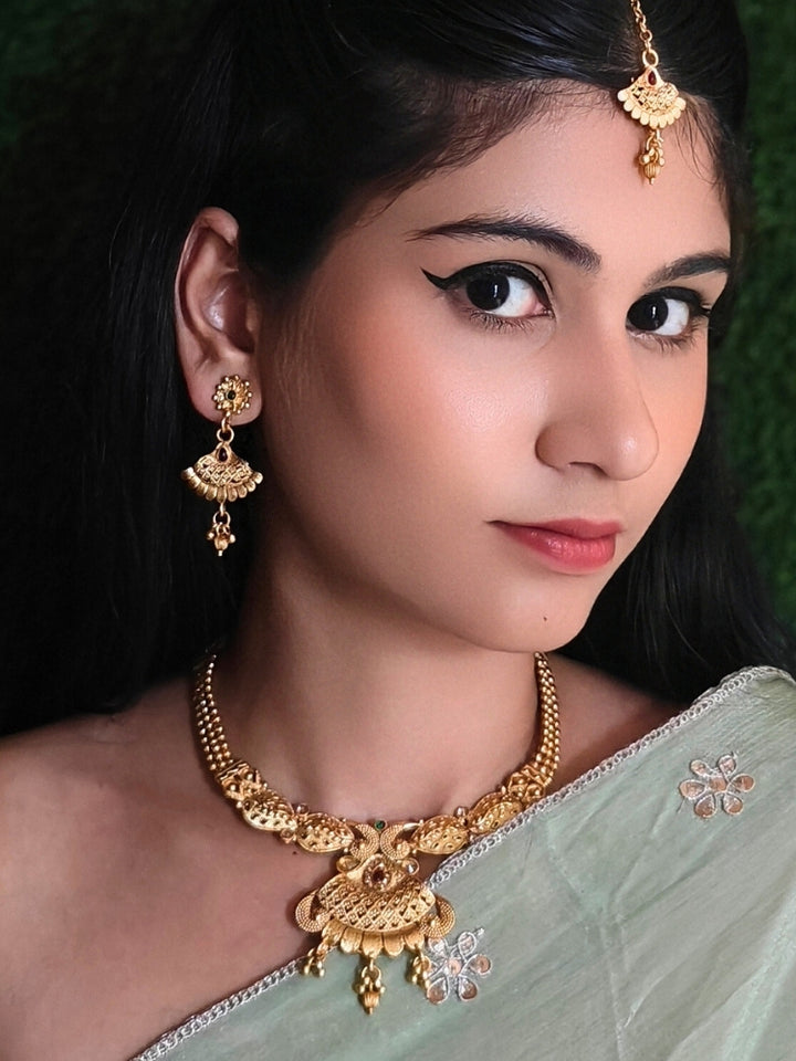 Close-up of a woman wearing an ornate traditional Rajwadi gold Collar jewellery set ,Earrings and Mangtikka with Colored Stones. Festive Diwali outfit enhanced with a Rajwadi artificial necklace. Festive look completed with a luxury Rajwadi imitation necklace.