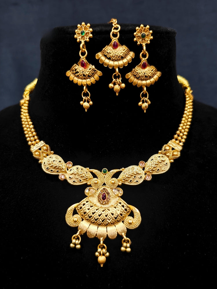 Close-up of an ornate traditional Rajwadi gold Collar jewellery set ,Earrings and Mangtikka with Colored Stones. Festive Diwali outfit enhanced with a Rajwadi artificial necklace. Festive look completed with a luxury Rajwadi imitation necklace.