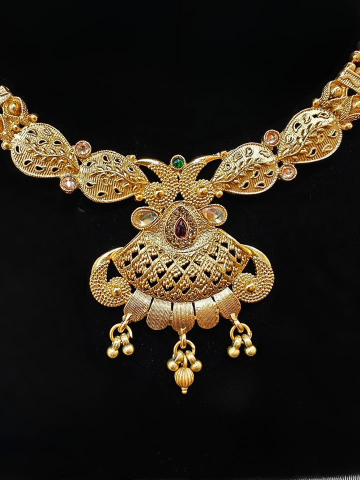 Close-up of an ornate traditional Rajwadi gold Collar jewellery set ,Earrings and Mangtikka with Colored Stones. Festive Diwali outfit enhanced with a Rajwadi artificial necklace. Festive look completed with a luxury Rajwadi imitation necklace.