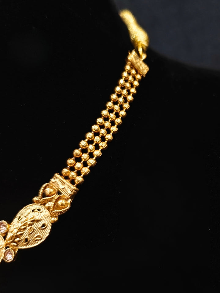 Close-up of an ornate traditional Rajwadi gold Collar jewellery set ,Earrings and Mangtikka with Colored Stones. Festive Diwali outfit enhanced with a Rajwadi artificial necklace. Festive look completed with a luxury Rajwadi imitation necklace.