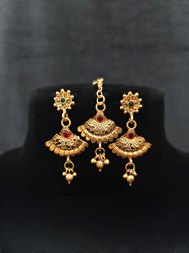 Close-up of an ornate traditional Rajwadi gold Collar jewellery set ,Earrings and Mangtikka with Colored Stones. Festive Diwali outfit enhanced with a Rajwadi artificial necklace. Festive look completed with a luxury Rajwadi imitation necklace.