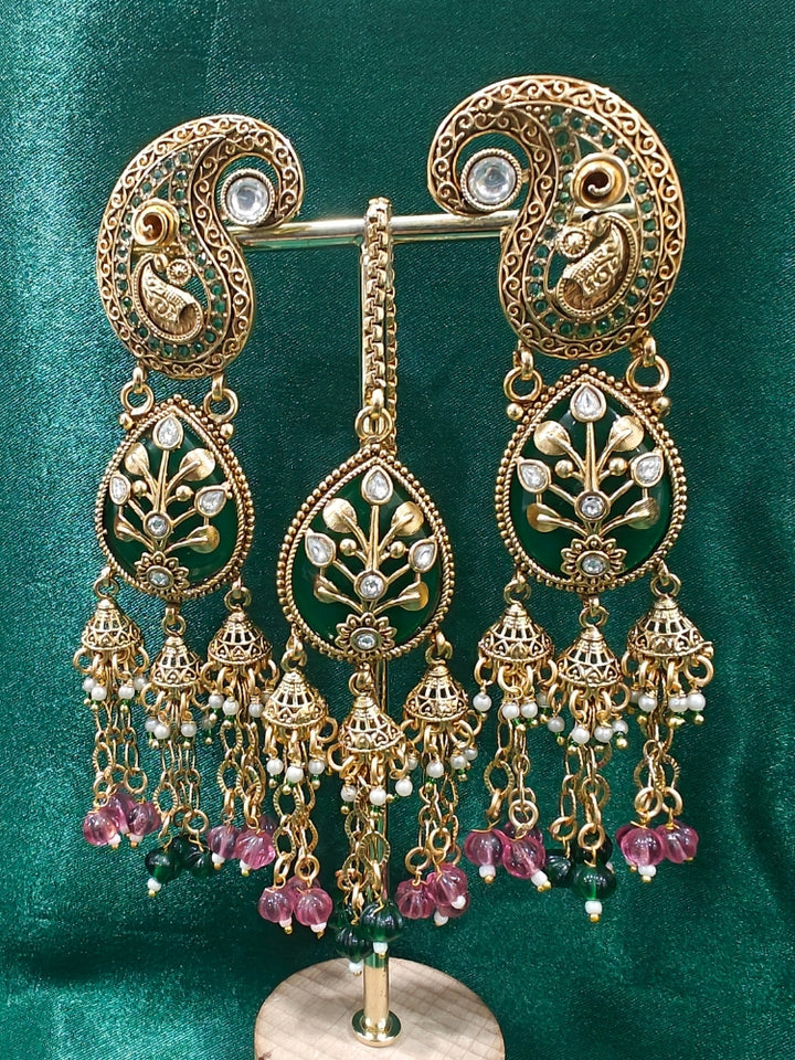 Close-up of an ornate traditional (Gold polish) Green and Mint Pink Collar jewellery set and earrings and maangtikka with Colored Stones, Kundan and Colored Beads. Bride wearing a colorful artificial Colored Stones set for reception night. Wedding function styling with a premium Colored Stone imitation necklace.