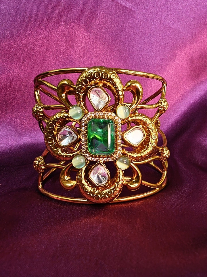 The Aziza Mint Green Bracelet (Adjustable) showcases an intricate floral design with a large Mint Green center stone, kundan and smaller Mint Green colored stones, set against a rich purple background—an ideal choice for wedding jewelry.