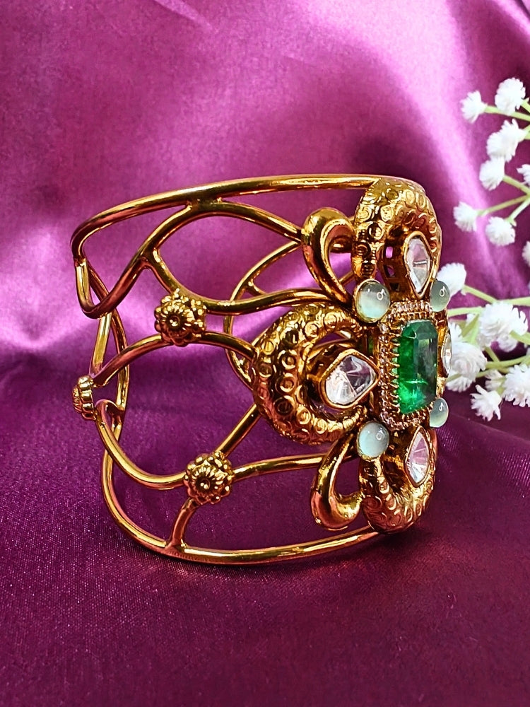 The Aziza Mint Green Bracelet (Adjustable) showcases an intricate floral design with a large Mint Green center stone, kundan and smaller Mint Green colored stones, set against a rich purple background—an ideal choice for wedding jewelry.