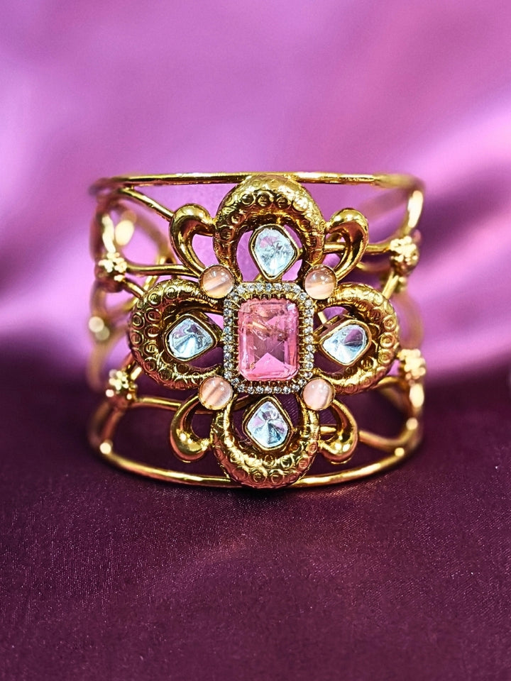 The Aziza Mint Pink Bracelet (Adjustable) showcases an intricate floral design with a large Mint Pink center stone, kundan and smaller Mint Pink colored stones, set against a rich purple background—an ideal choice for wedding jewelry.