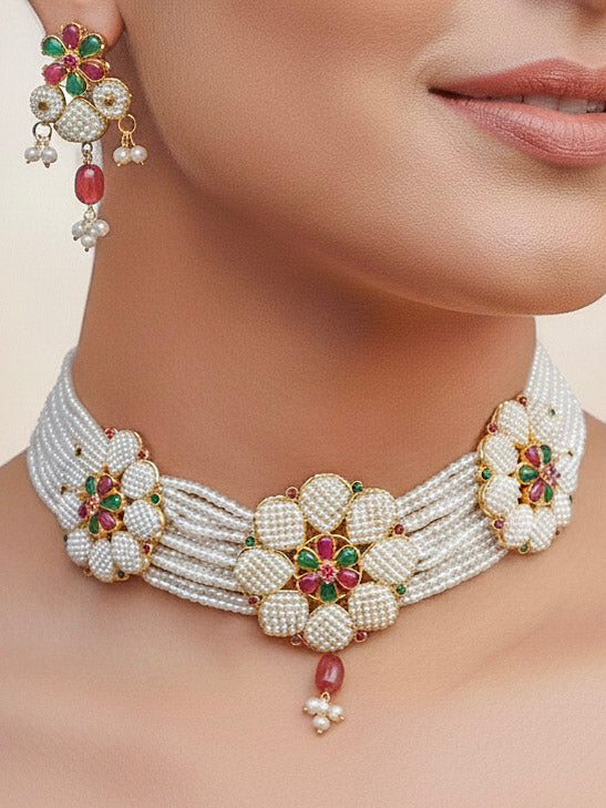 Close-up of a women wearing an ornate traditional (Bright Gold Polish) Red, Green and White Choker jewellery set and earrings and Ring with Pearls and Red & Green Colored Stones. Mehendi ceremony look completed with a handcrafted Pearl jewelry set. Woman wearing a vibrant Pearl artificial jewelry set for celebrations.