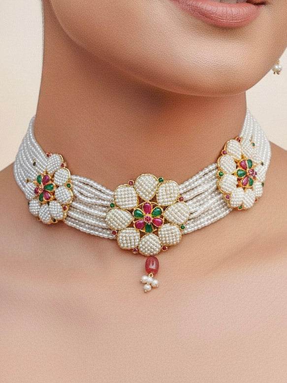 Close-up of a women wearing an ornate traditional (Bright Gold Polish) Red, Green and White Choker jewellery set and earrings and Ring with Pearls and Red & Green Colored Stones. Mehendi ceremony look completed with a handcrafted Pearl jewelry set. Woman wearing a vibrant Pearl artificial jewelry set for celebrations.