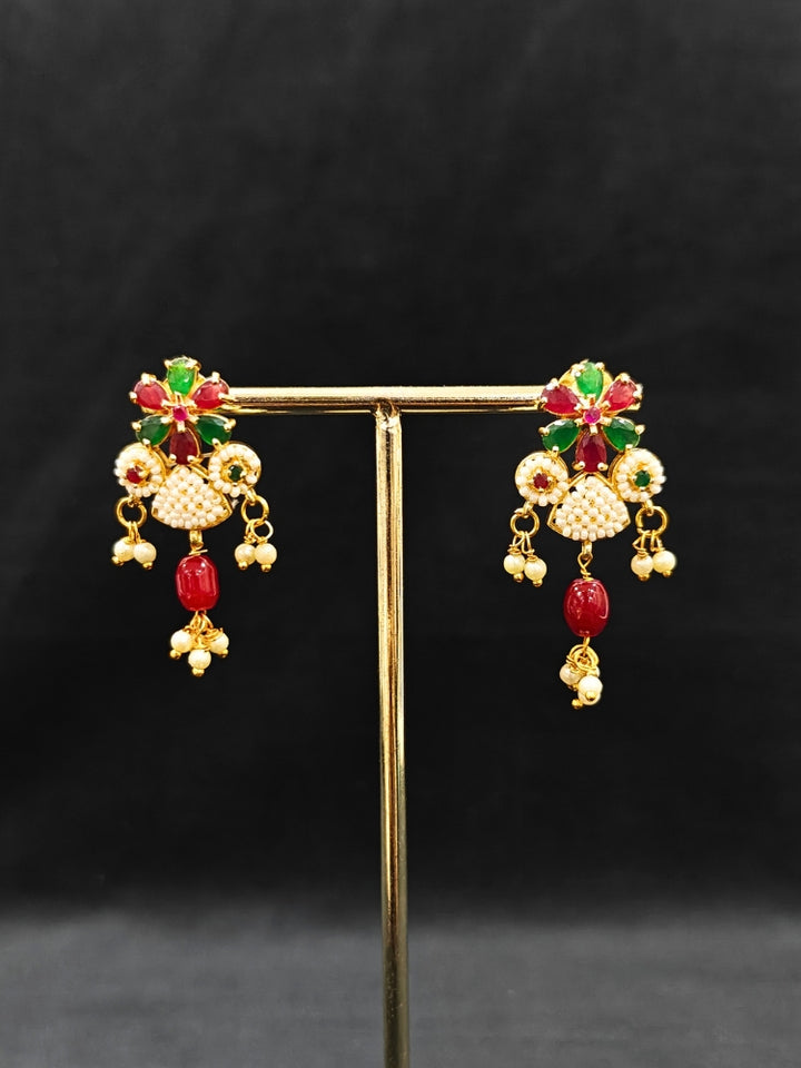 Close-up of an ornate traditional (Bright Gold Polish) Red, Green and White Choker jewellery set and earrings and Ring with Pearls and Red & Green Colored Stones. Mehendi ceremony look completed with a handcrafted Pearl jewelry set. Woman wearing a vibrant Pearl artificial jewelry set for celebrations.
