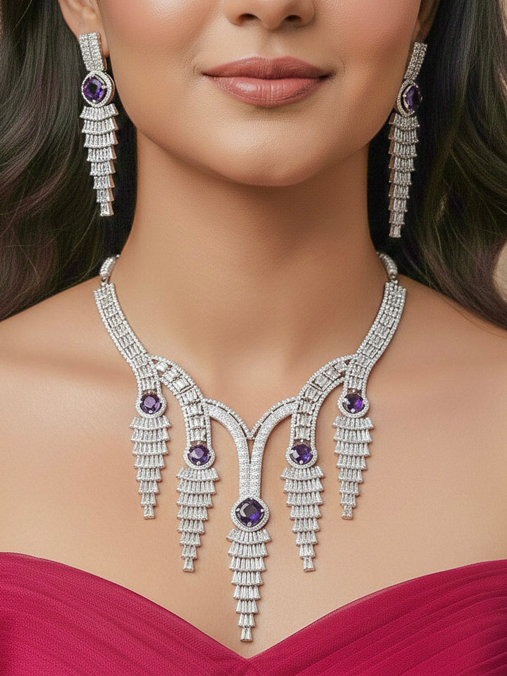 "A close-up shot of a bride wearing a stunning artificial diamond necklace with Purple colored stone and matching earrings and matching maangtikka, designed to complement bridal attire. This affordable diamond necklace set is perfect for brides seeking luxurious but cost-effective wedding jewelry in India."
