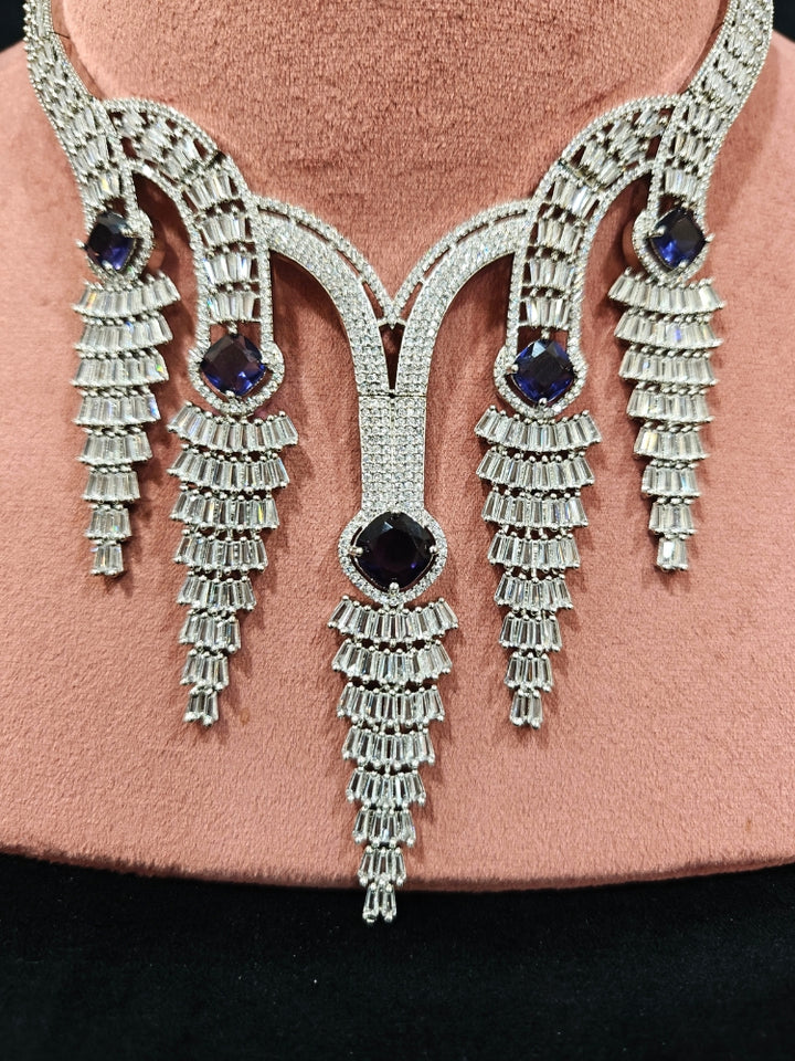 Close-up of an ornate Western Silver Diamond Collar jewellery set, earrings and Mangtikka with American Diamond and Purple Color Stone. Close-up of a Wedding, Reception look featuring a premium American diamond necklace.