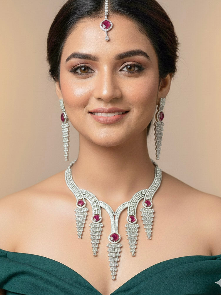 "A bride-to-be wearing an exquisite artificial diamond necklace with red colored stone and matching earrings and matching maangtikka, designed for the perfect engagement look. This stunning artificial diamond jewelry set offers luxury and sophistication while being an affordable alternative to natural diamonds."
