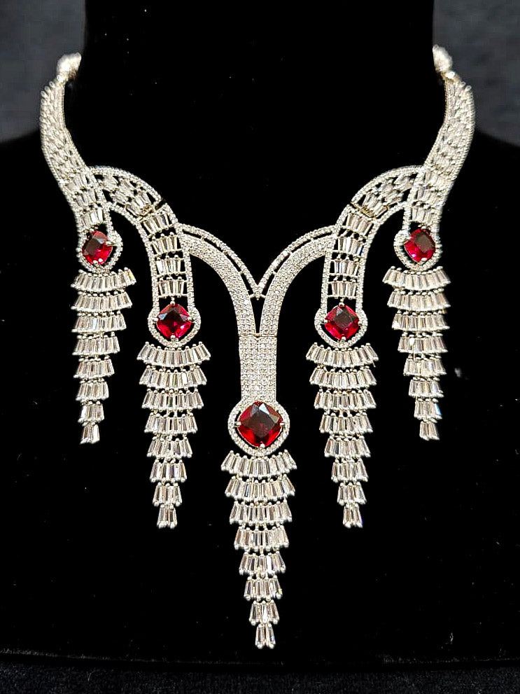 Close-up of an ornate Western Silver Diamond Collar jewellery set, earrings and Mangtikka with American Diamond and Red Color Stone. Close-up of a Wedding, Reception look featuring a premium American diamond necklace.