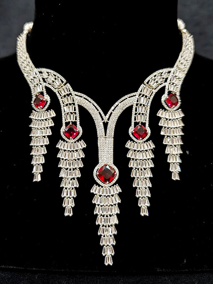 Close-up of an ornate Western Silver Diamond Collar jewellery set, earrings and Mangtikka with American Diamond and Red Color Stone. Close-up of a Wedding, Reception look featuring a premium American diamond necklace.