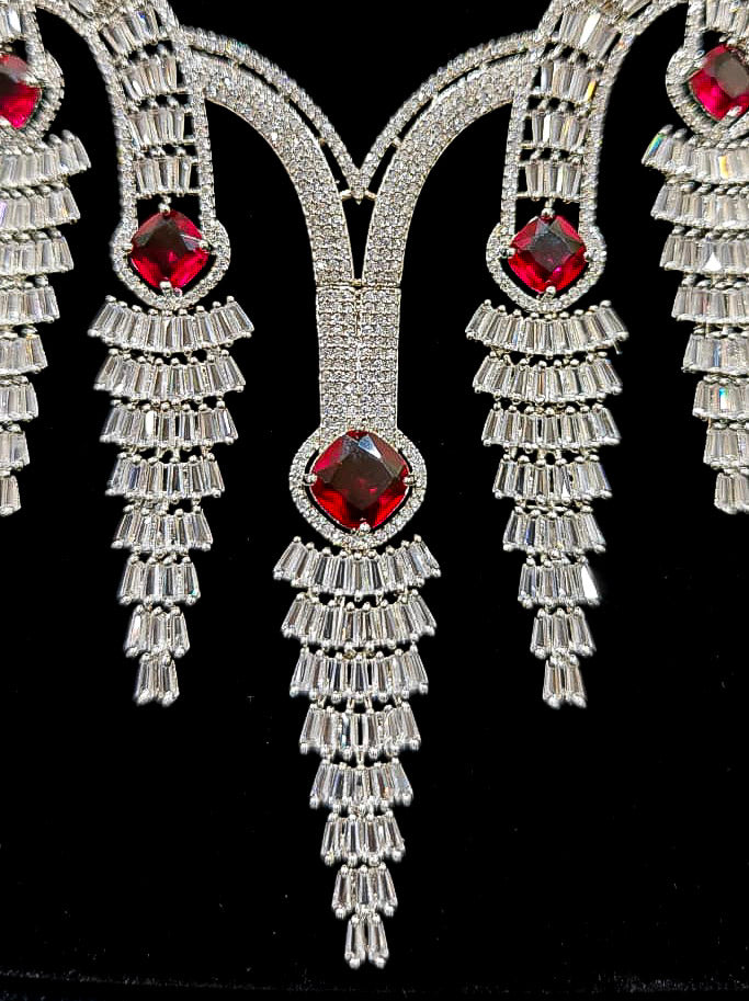 Close-up of an ornate Western Silver Diamond Collar jewellery set, earrings and Mangtikka with American Diamond and Red Color Stone. Close-up of a Wedding, Reception look featuring a premium American diamond necklace.