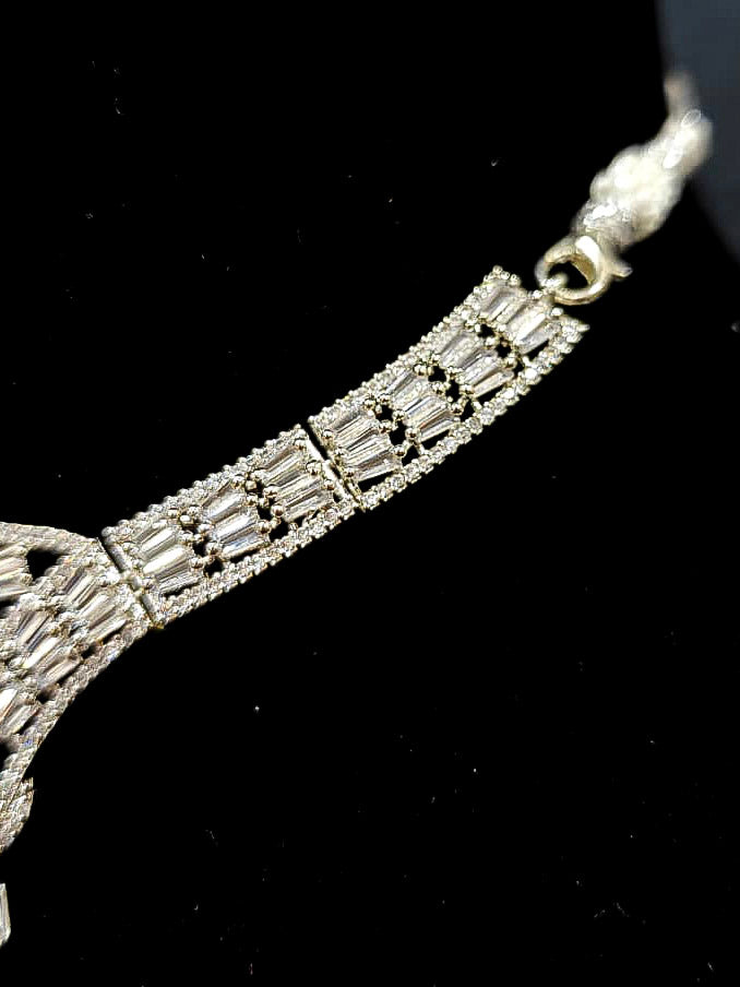 Close-up of an ornate Western Silver Diamond Collar jewellery set, earrings and Mangtikka with American Diamond and Red Color Stone. Close-up of a Wedding, Reception look featuring a premium American diamond necklace.
