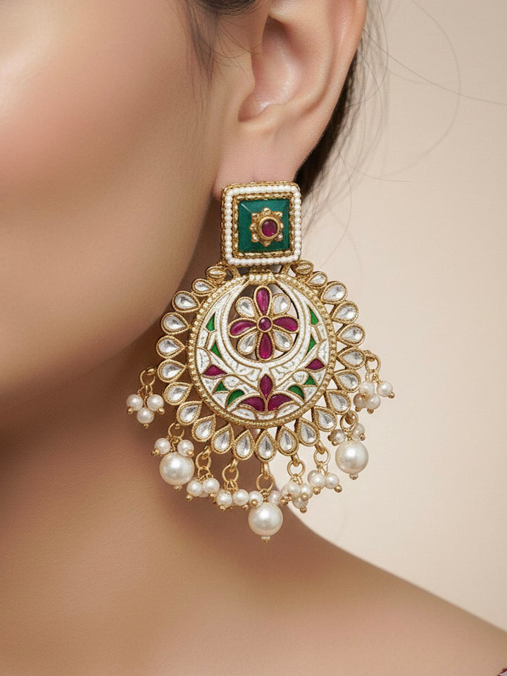 Close-up of a woman wearing an ornate traditional Heritage gold Collar jewellery set and earrings and maangtikka with Pearls, Meenakari, Green Colored Stones and Kundan. Bride wearing a heritage-inspired artificial necklace set for her wedding ceremony. Close-up of intricate Meenakari detailing in imitation bridal jewelry.