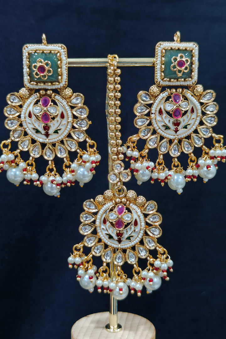 Close-up of an ornate traditional Heritage gold Collar jewellery set and earrings and maangtikka with Pearls, Meenakari, Green Colored Stones and Kundan. Traditional Indian bridal look completed with a heritage artificial jewelry set. Close-up of detailed enamel craftsmanship in Meenakari jewelry.