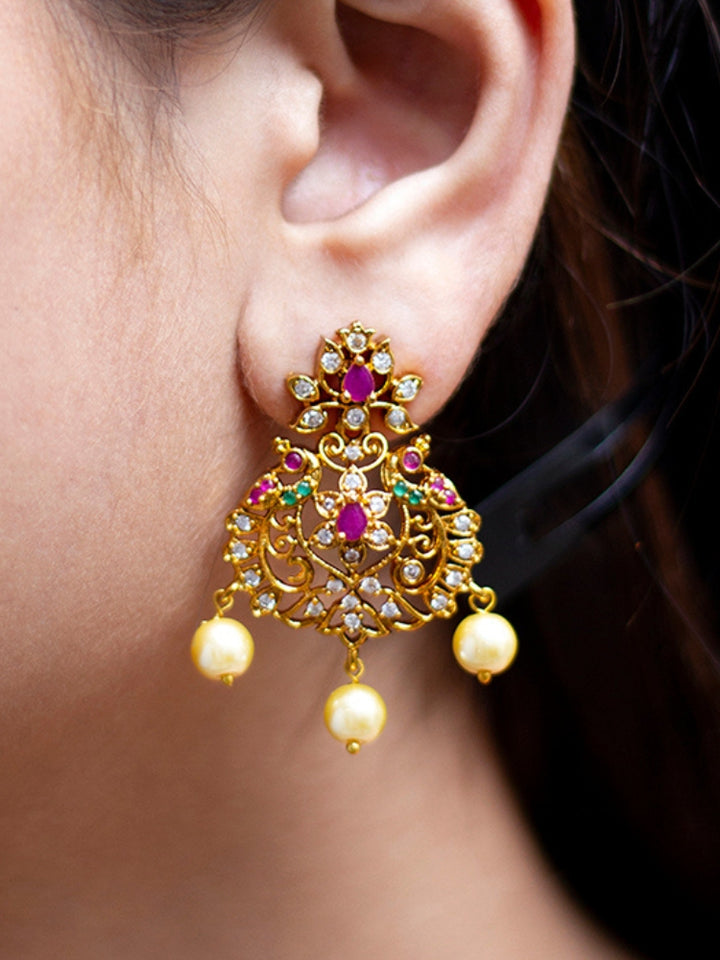 Close-up of a woman wearing an ornate traditional (Gold Polish) Earrings With American Diamond, Colored Stones and Pearls. Woman wearing statement artificial American Diamond earrings for a wedding guest look in India. Festive saree look completed with premium imitation American Diamond earrings.
