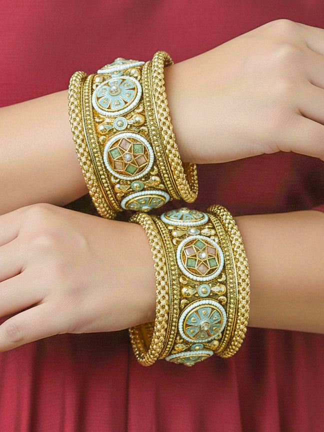 Close-up of a woman wearing an ornate traditional Rajwadi gold Bangle with Mint Pink & Mint Green Colored Stone, Meenakari, Bandhai Work and Pearls. Woman wearing bridal artificial Rajwadi bangles for a grand celebration. Luxury artificial Rajwadi bangles styled for a wedding function. Close-up of high-quality imitation Meenakari bangles for bridal wear.